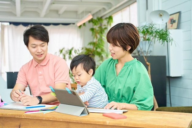 A woman and a man holding a baby and operating a computer indoors