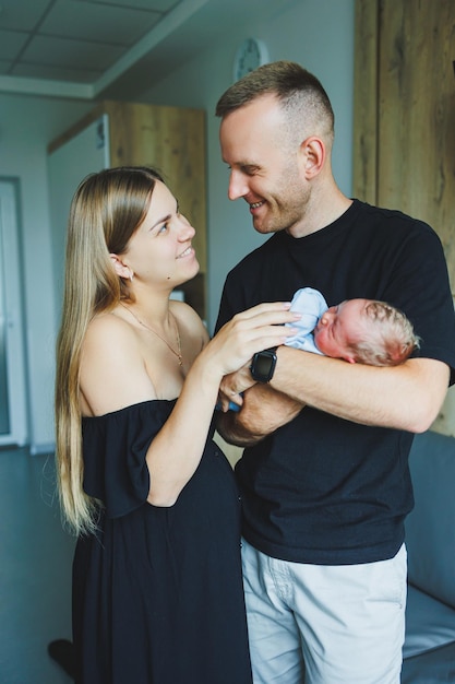 Woman and man holding a newborn Mom dad and baby Closeup Portrait of young smiling family with newborn on the hands Happy family on a background