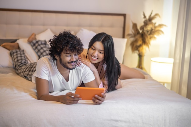 Woman and man lying on stomach with tablet