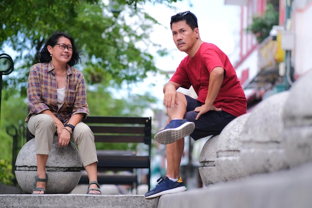 Photo a woman and a man sitting casually on stone benches