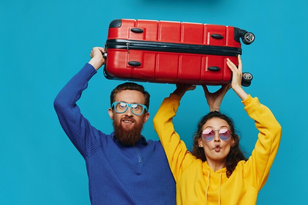 Woman and man smile suitcases in hand with yellow and red suitcase smile fun on blue background packing for a trip family vacation trip