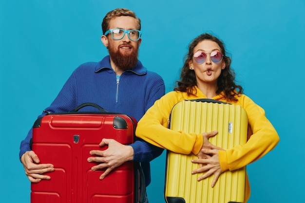 Woman and man smile suitcases in hand with yellow and red suitcase smile fun on blue background packing for a trip family vacation trip