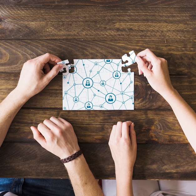 Photo woman and man solving network connectivity puzzle over wooden desk