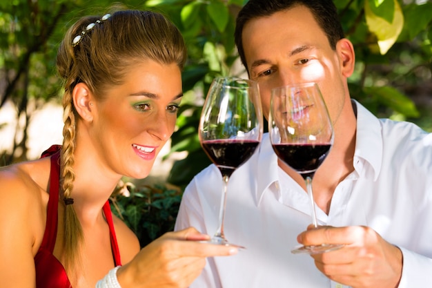 Женщина и мужчина в винограднике пьют вино