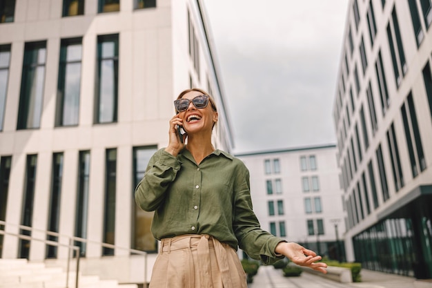 Photo woman manager talking phone with client whiile standing on modern building background