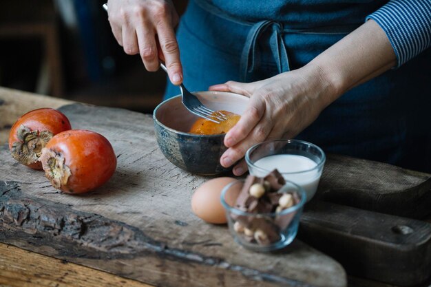 Woman mashing persimmonfor preparing dessert