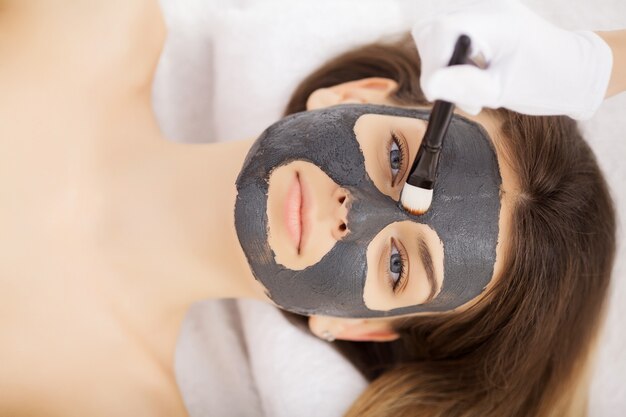 Donna in maschera sul viso nel salone di bellezza spa.