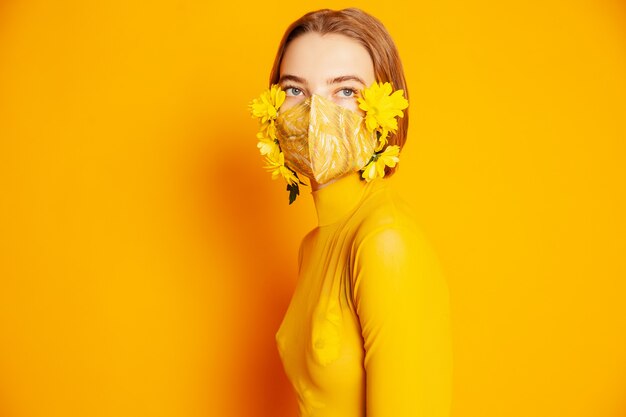 Woman in mask with yellow flowers in studio