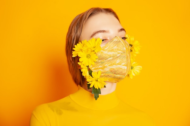 Woman in mask with yellow flowers in studio