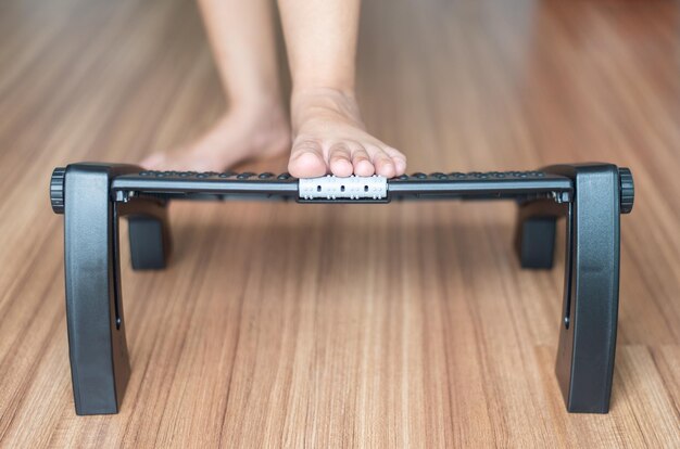 Photo woman massage with foot rest under desk for relieve plantar fasciitis at home