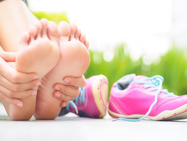 Woman massaging her painful foot while exercising. Running sport injury concept.