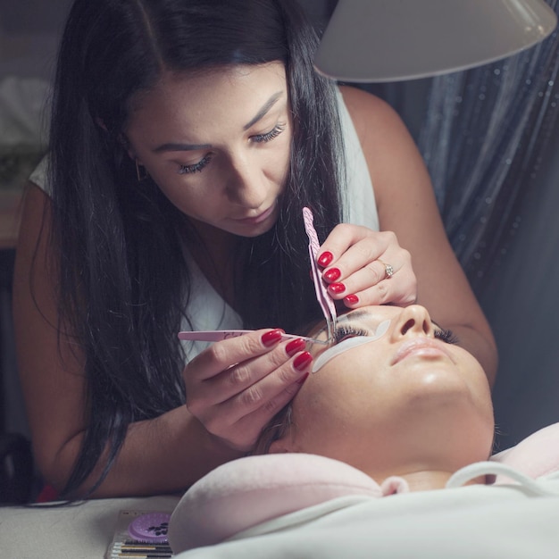 Woman master in salon making eyelash extension