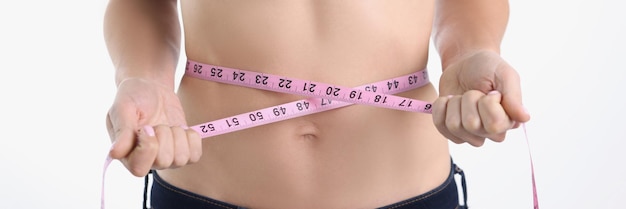 A woman measures her waist with a tape closeup blurry the concept of weight loss marathon keto