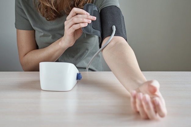 Woman measuring blood pressure herself with digital pressure monitor. Health care and medical concept