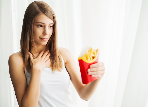 Woman Measuring Body Weight On Weighing Scale Holding Unhealthy Junk Food