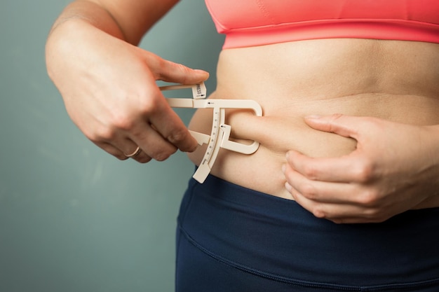 Woman measuring her body skin fat with fat caliper