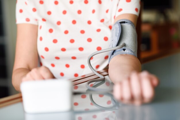 Woman measuring her own blood pressure at home.