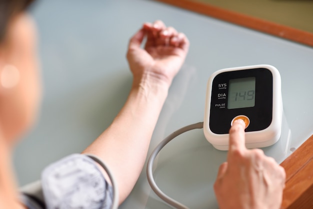 Woman measuring her own blood pressure at home.