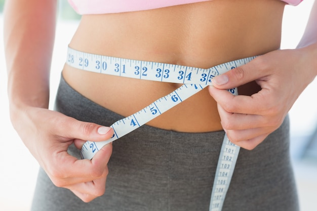 Woman measuring waist in fitness studio