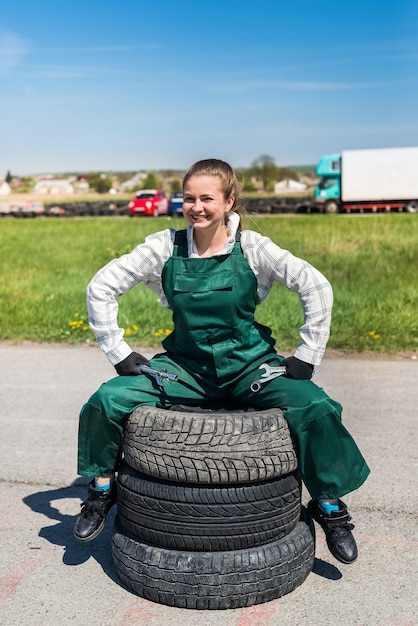 Woman mechanic posing with spanners and tyres