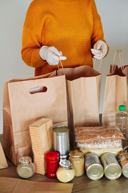 寄付のために食品を梱包する医療用手袋の女性