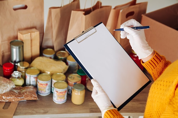 Photo woman in medical gloves packing food for donation