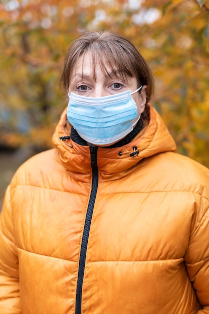 Woman in a medical mask in the autumn park