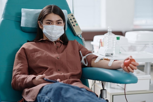Woman in Medical Mask Making Blood Donation in Hospital