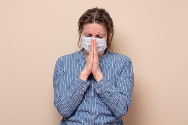 Женщина в медицинской маске молится о помощи Бога во время пандемии коронавируса
