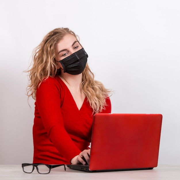 woman in a medical mask, remotely working at the computer on white.