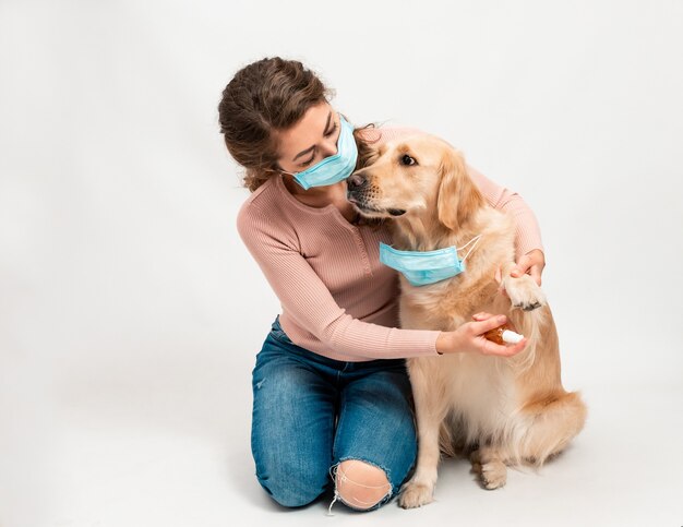 Donna in maschera protettiva medica disinfetta le zampe dei cani con un disinfettante