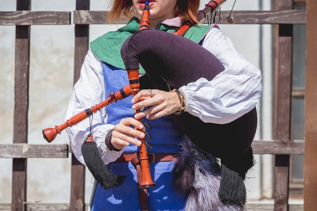 Woman in medieval clothes playing on a bagpipe