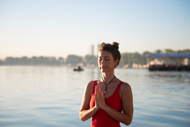 海の横で日の出の間に瞑想する女性