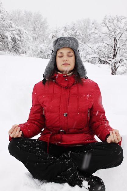 Donna meditando in inverno in un parco innevato