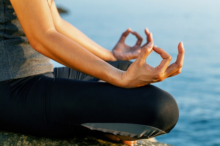The woman meditating in a yoga pose on the tropical beach. 