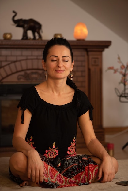 Foto una donna che medita in uno studio di yoga con un camino dietro di lei.