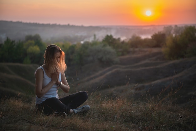 Meditazione della donna o pregare al tramonto