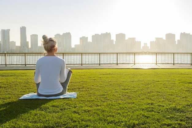 woman meditation in yoga relaxing in a park in front of the sea at sunrise healthy mind wellbeing and wellness soul concept