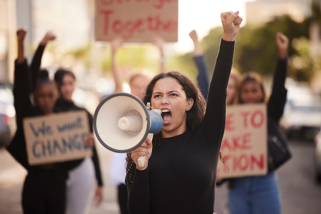 Foto donna megafono e pugno nella protesta della comunità per cambiare la violenza di genere o l'uguaglianza in città attivista di donne arrabbiate che si uniscono in marcia per i diritti umani o l'azione del governo