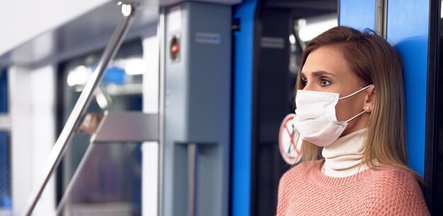 Woman in metro station wearing protective surgical hygiene mask on face prevent from risk of coronavirus