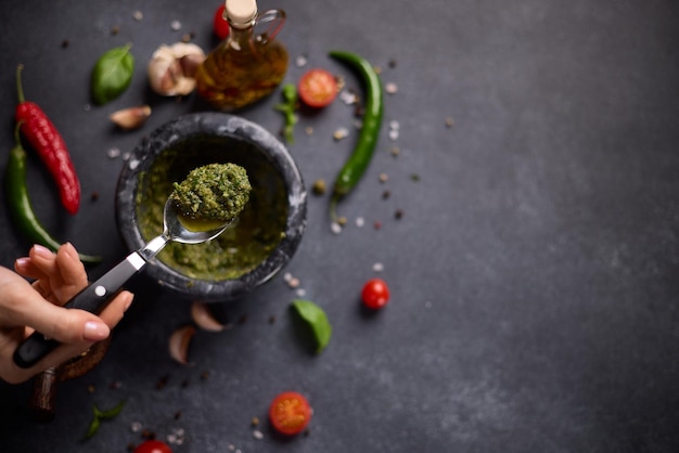 Woman mixing green sauce in a stone marble mortar