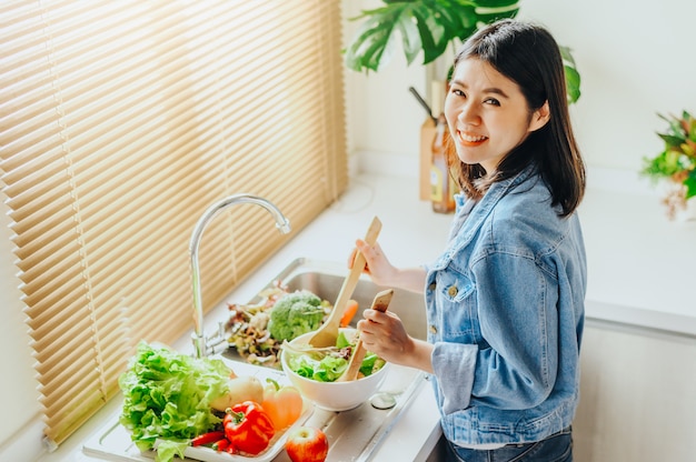Photo woman mixing salad in bowl while cooking at home