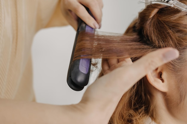 Woman model is dressing her hair by the hairdresser in studio room