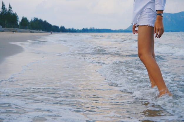 Foto gamba del modello della donna con la vista del mare dell'onda