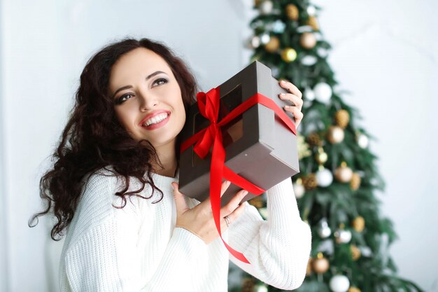 Woman model in a red dress in a photo studio holding a New Year's gift in her hands.