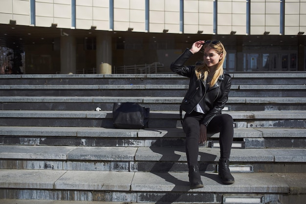 Woman model sits on stairs near a building on the street in autumn High quality photo
