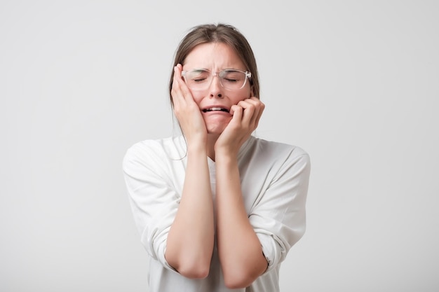 Woman in modern glasses covering ears and shouting