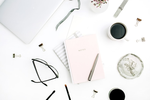 파스텔 핑크 노트북, 안경, 커피 컵, 야생 꽃과 흰색 배경에 액세서리와 여자 현대 홈 오피스 책상