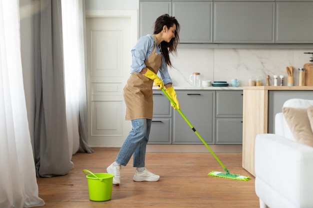 Photo woman mopping floor in bright kitchen interior