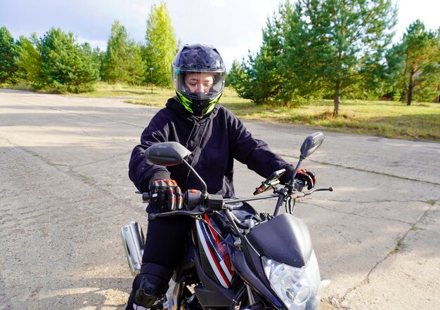 写真 ヘルメットをかぶった女性のオートバイ運転手オートバイの手袋モーターサイクルのブーツ